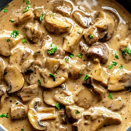Beef stroganoff with sliced mushrooms in creamy sauce in black pan