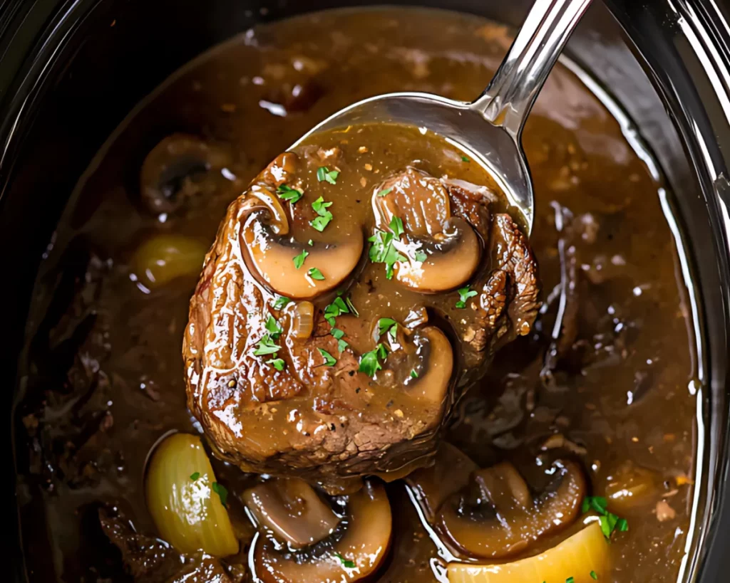 Serving Slow Cooker Round Steak and Gravy with a spoon in pot