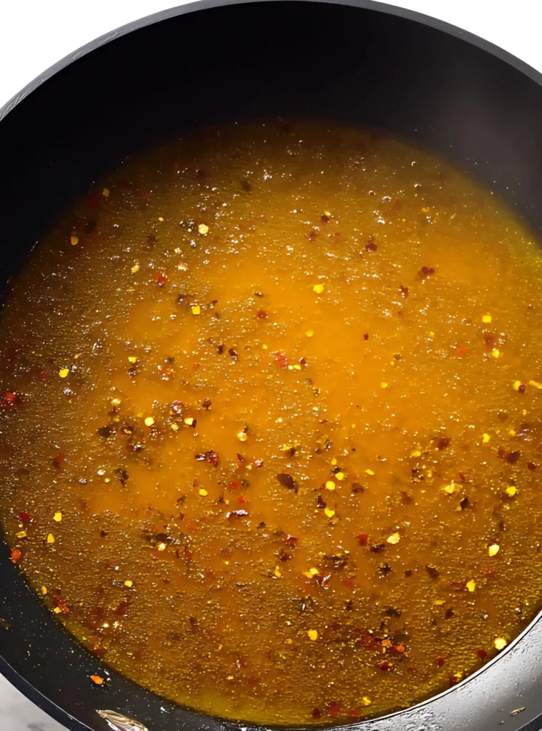 Broth with spices simmering in a black skillet