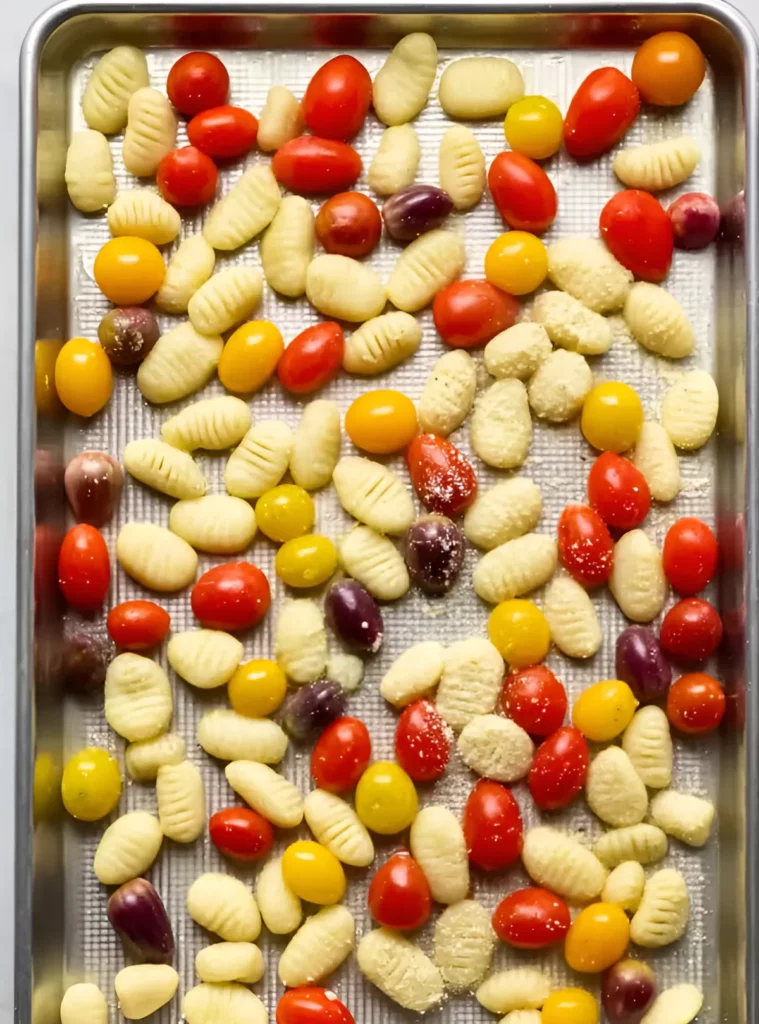 Raw gnocchi and tomatoes on baking tray