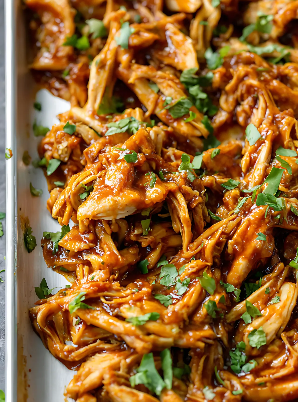 Close-up of saucy shredded chicken with herbs