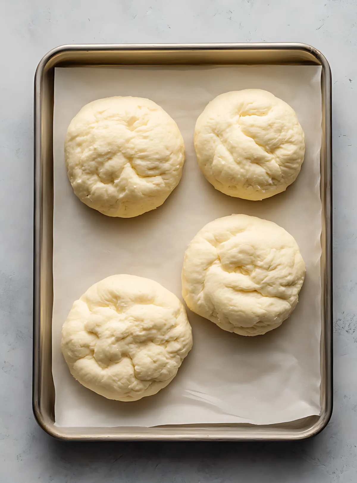 Four raw cloud bread rounds on parchment-lined tray
