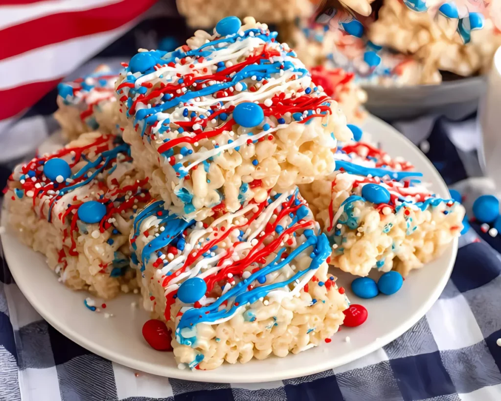 Plate of drizzled patriotic rice krispie treats on blue checkered cloth