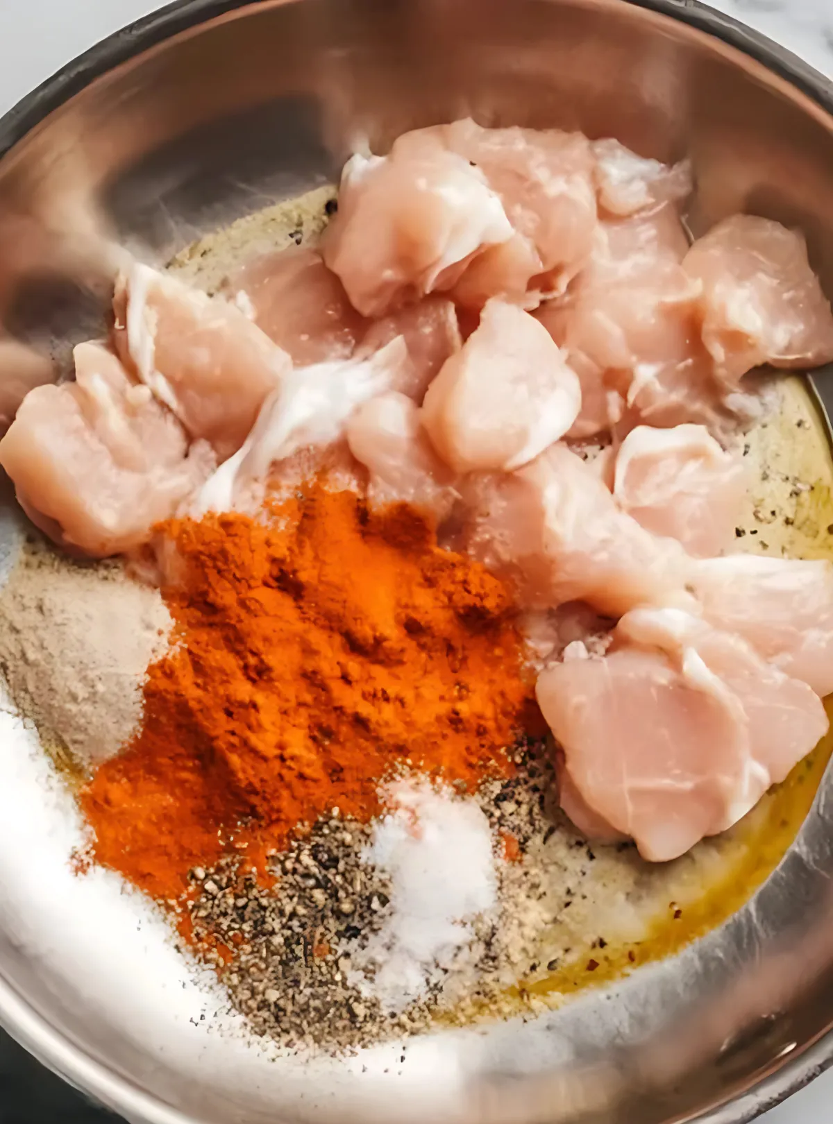 Raw chicken with spices in skillet