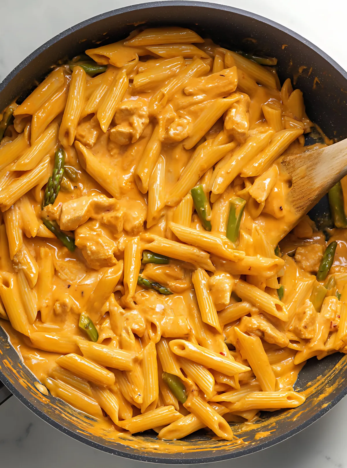 creamy chipotle chicken pasta cooking with wooden spoon