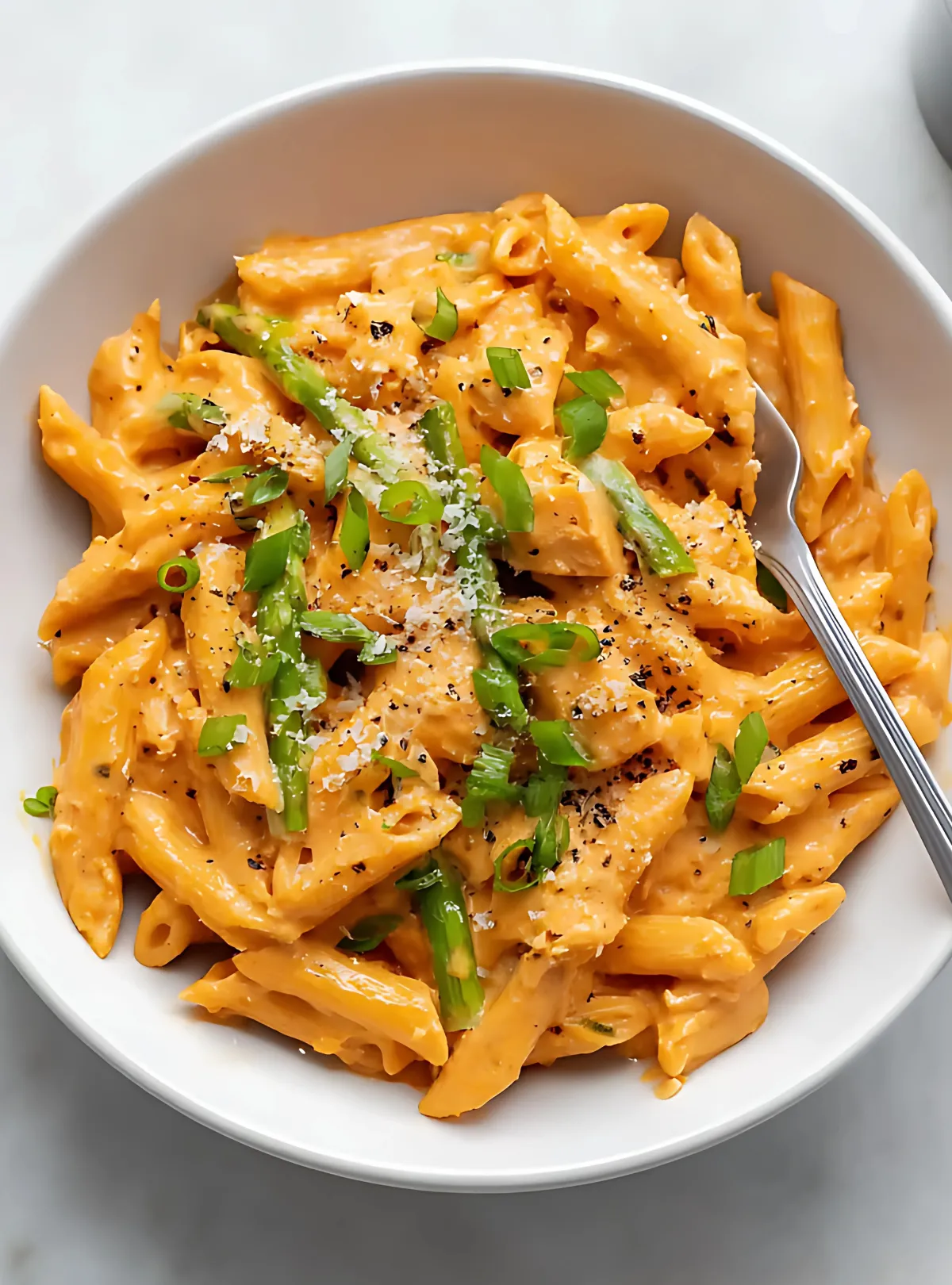 creamy chipotle chicken pasta served in a white bowl with fork