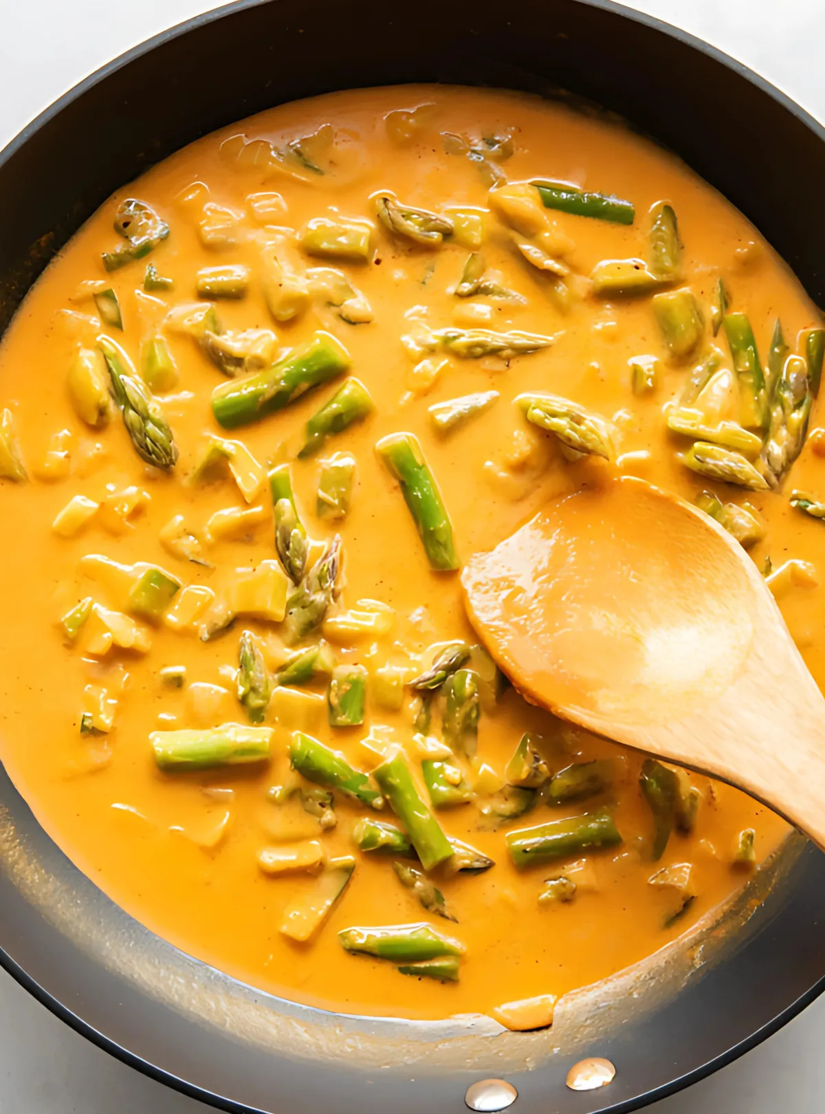 creamy chipotle sauce with asparagus cooking in a black skillet