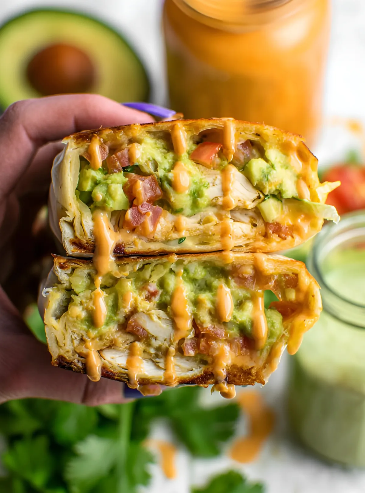 hand holding burrito with chipotle drizzle