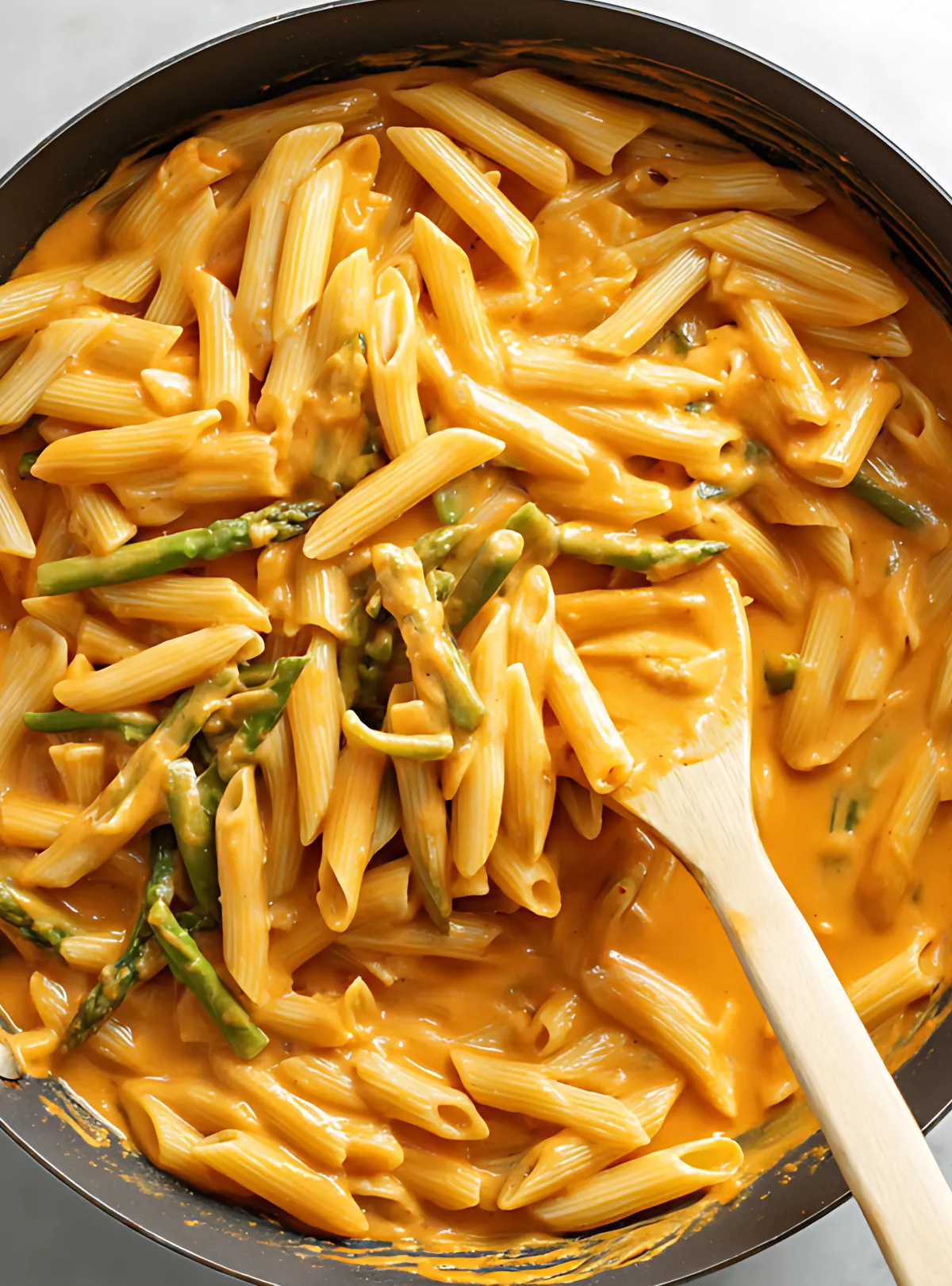 penne pasta added to creamy chipotle sauce in a skillet