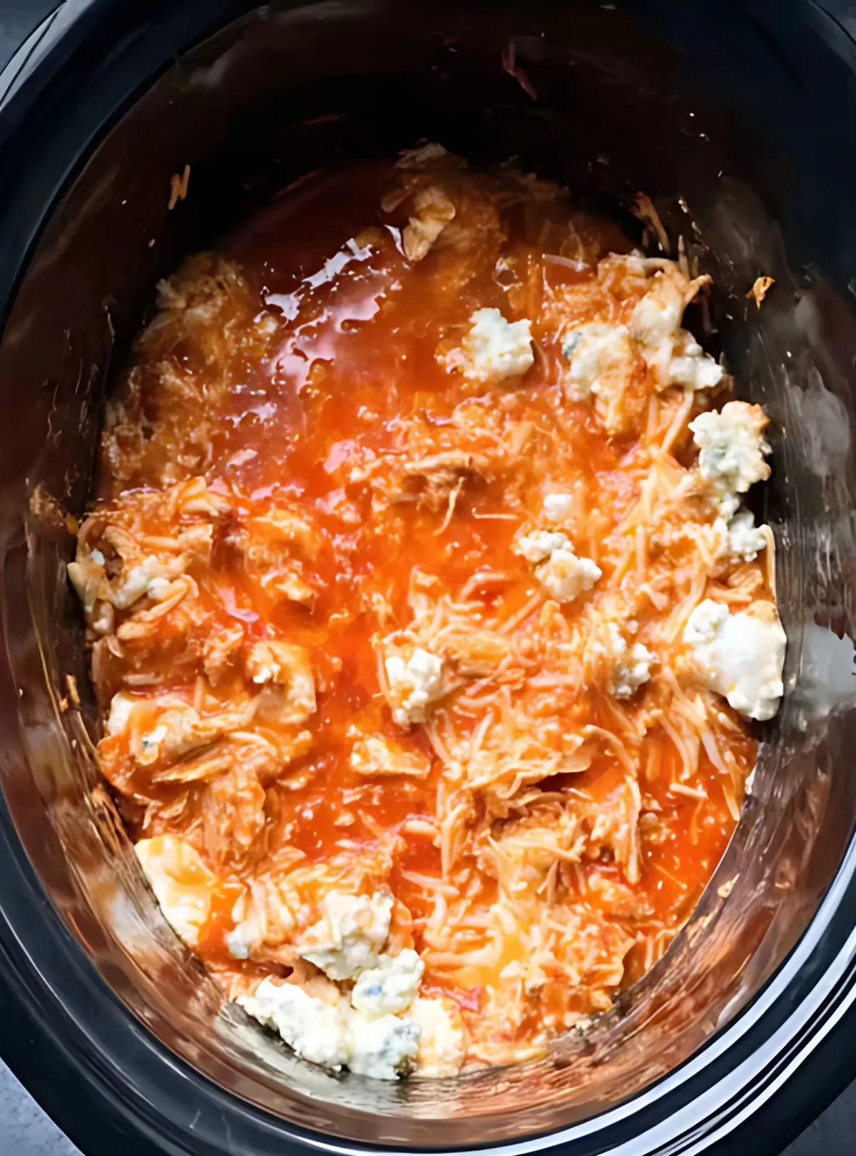 Cooked buffalo chicken mix with blue cheese in slow cooker