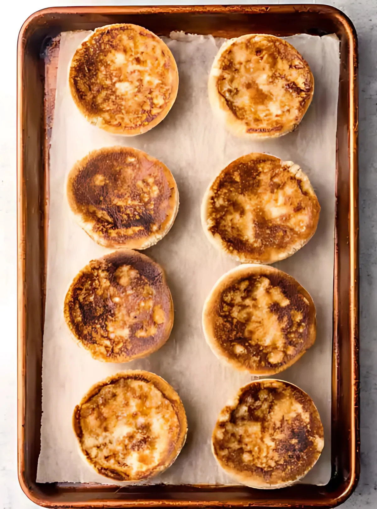 Eight toasted muffin halves on a baking sheet