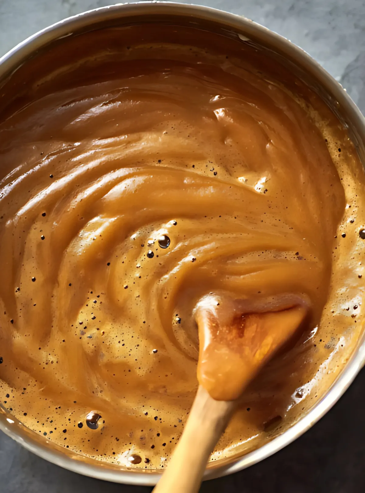Foamy caramel sauce with wooden spoon