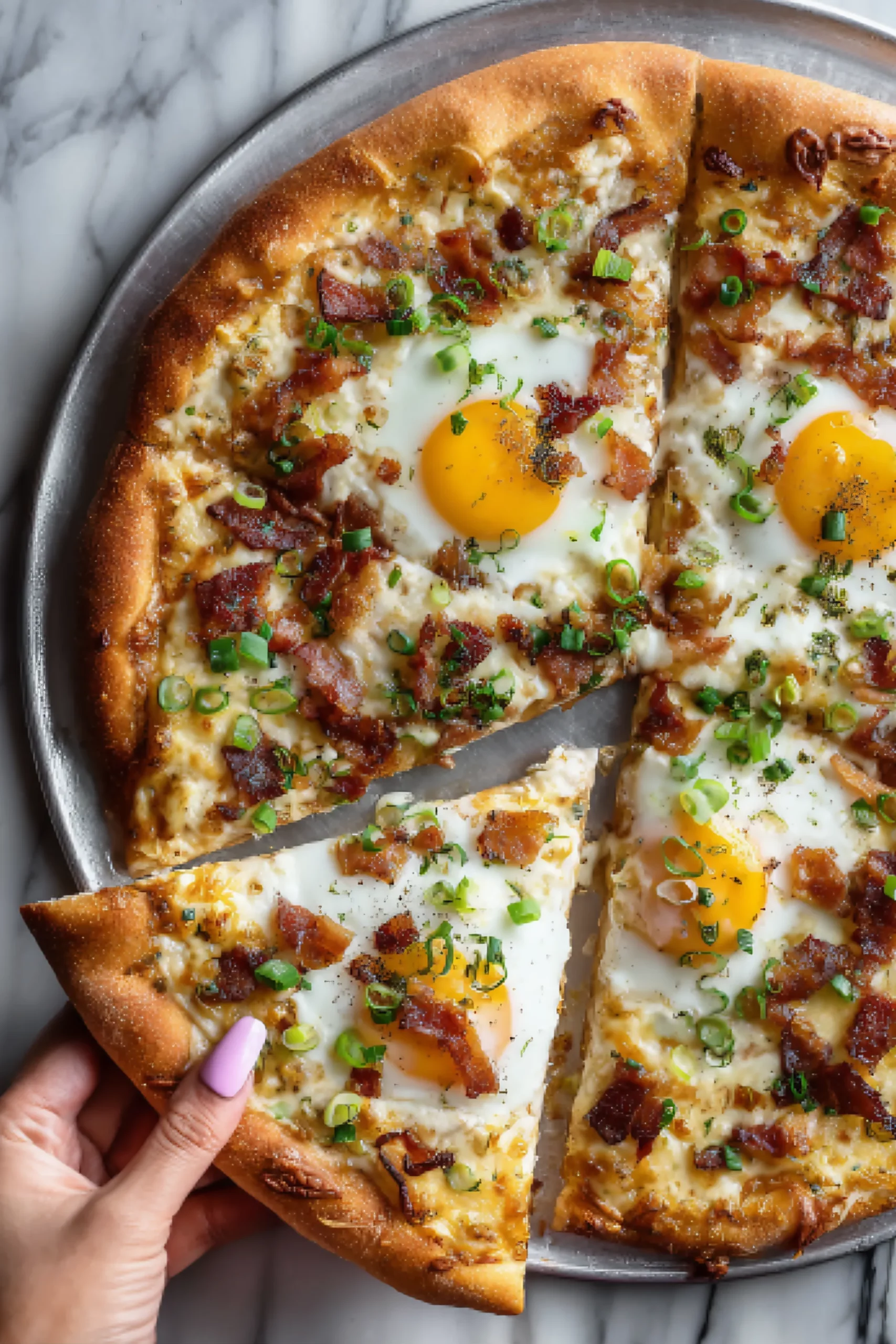 Hand holding slice of breakfast pizza with eggs