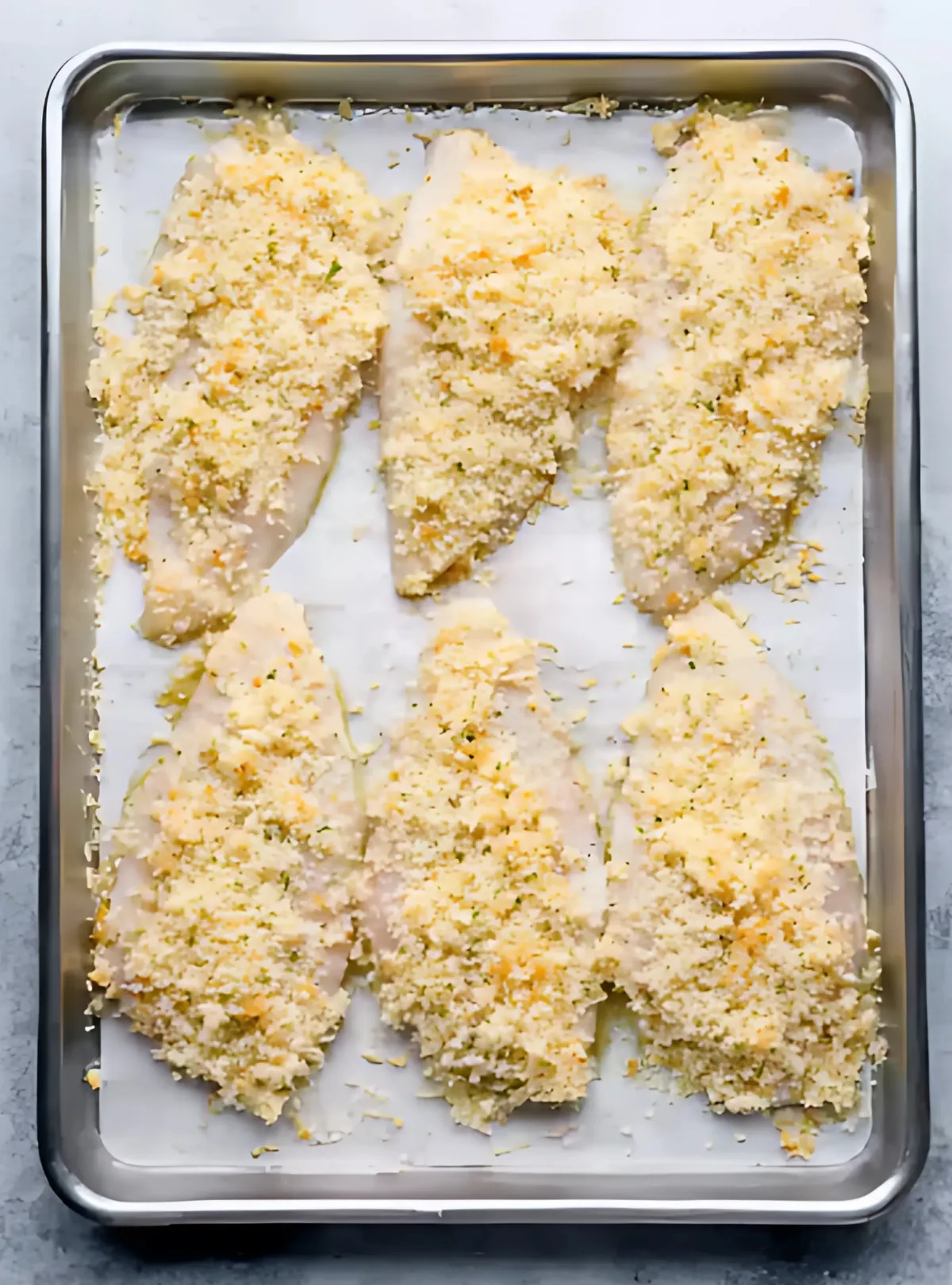 Raw tilapia fillets with crust on baking tray