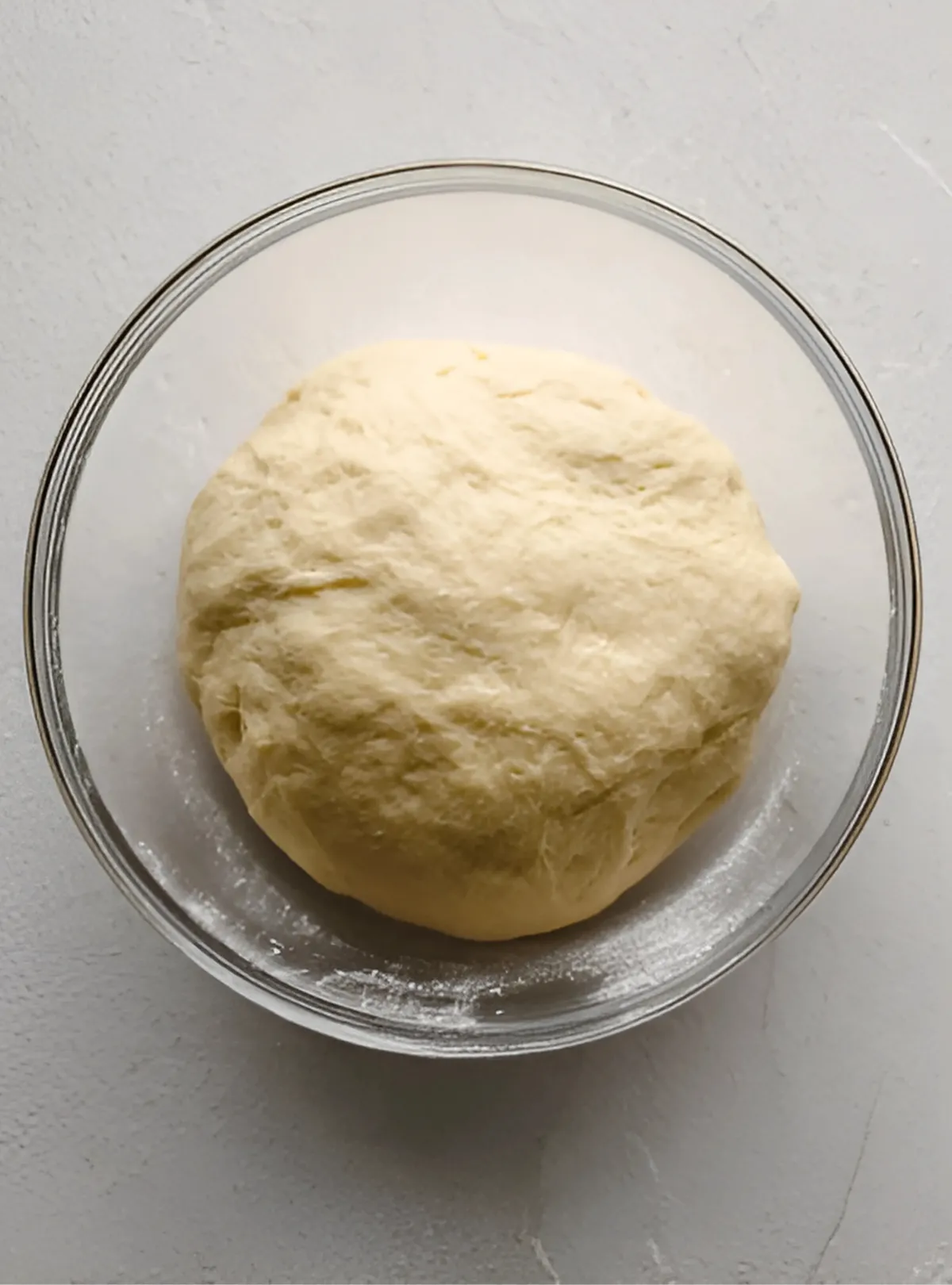 ball of pizza dough in glass bowl