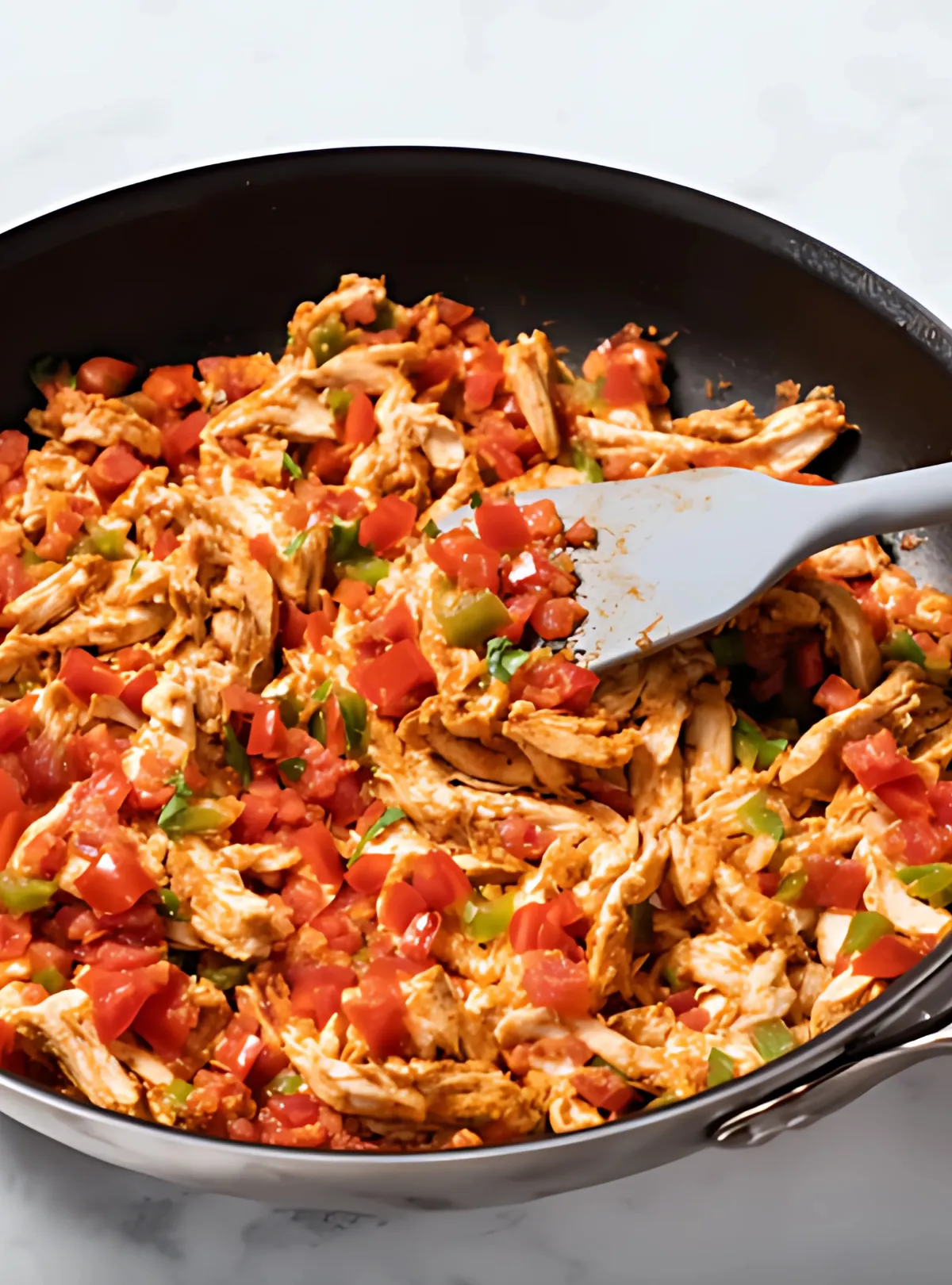 Shredded chicken with tomatoes in skillet