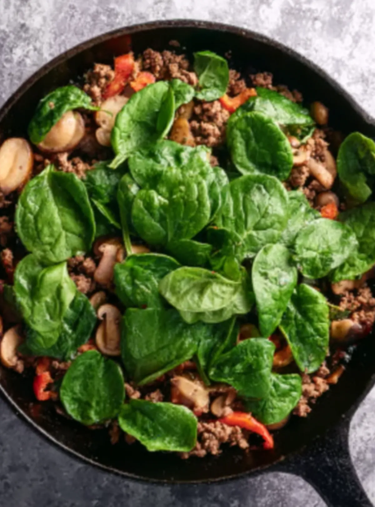 Spinach added to sausage mix in skillet