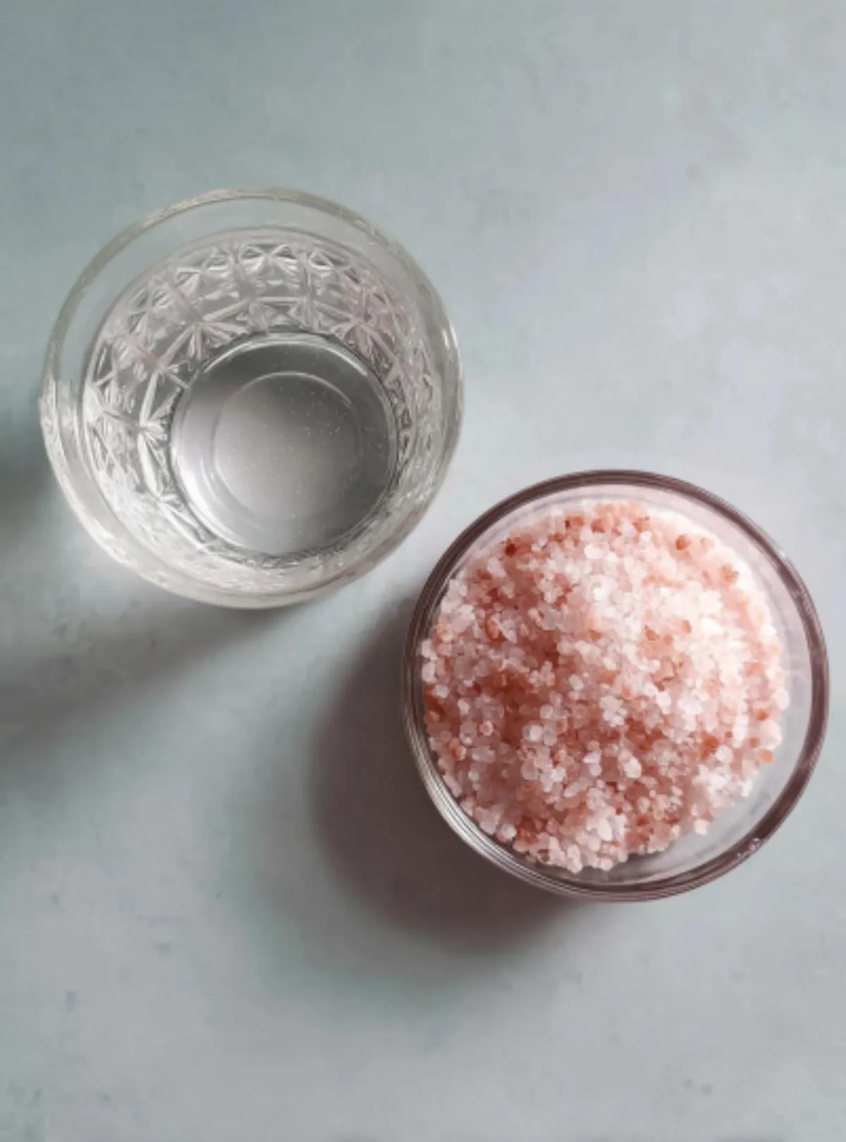 Top view glass of water and pink Himalayan salt in bowl