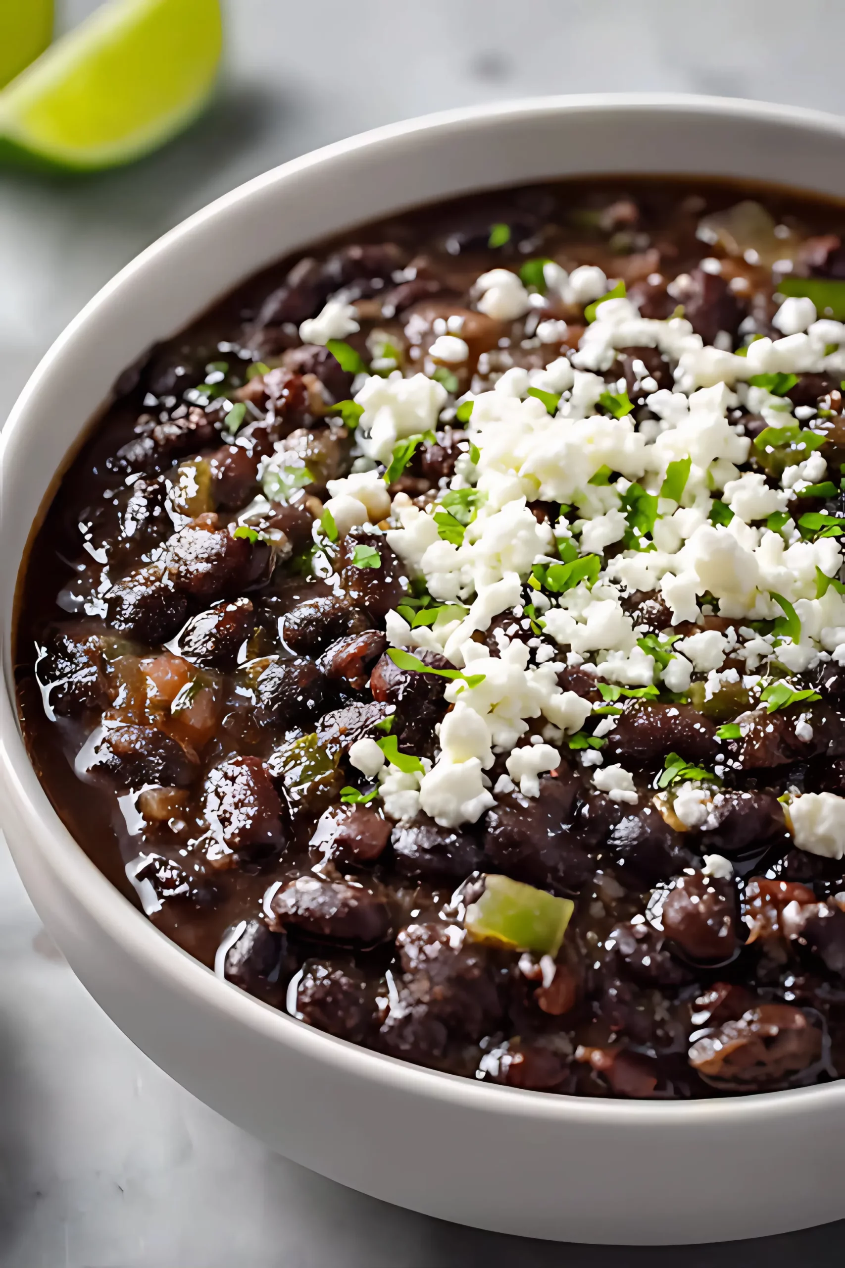 _close view of black beans in bowl with cheese and lime