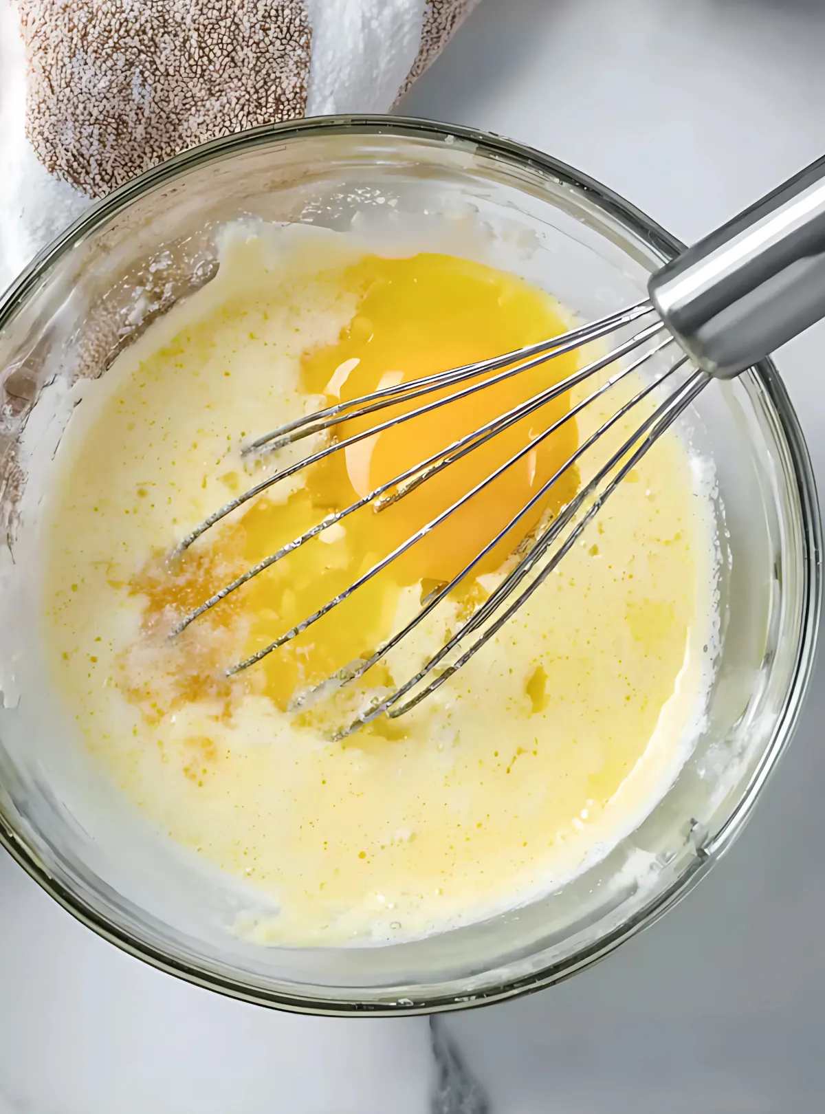 glass bowl with egg and milk mixture and whisk