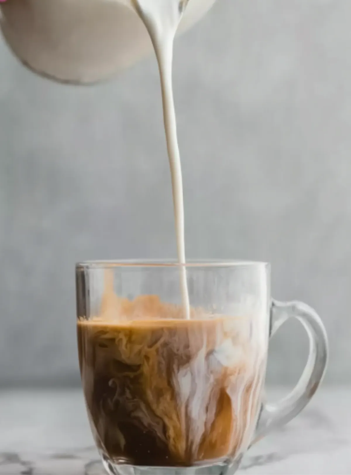 milk swirling in espresso in glass mug