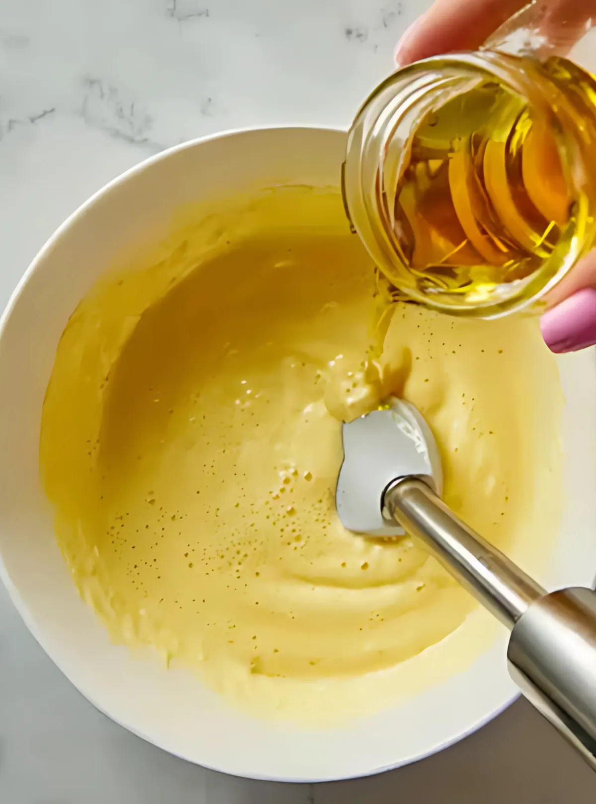 pouring oil into bowl with immersion blender