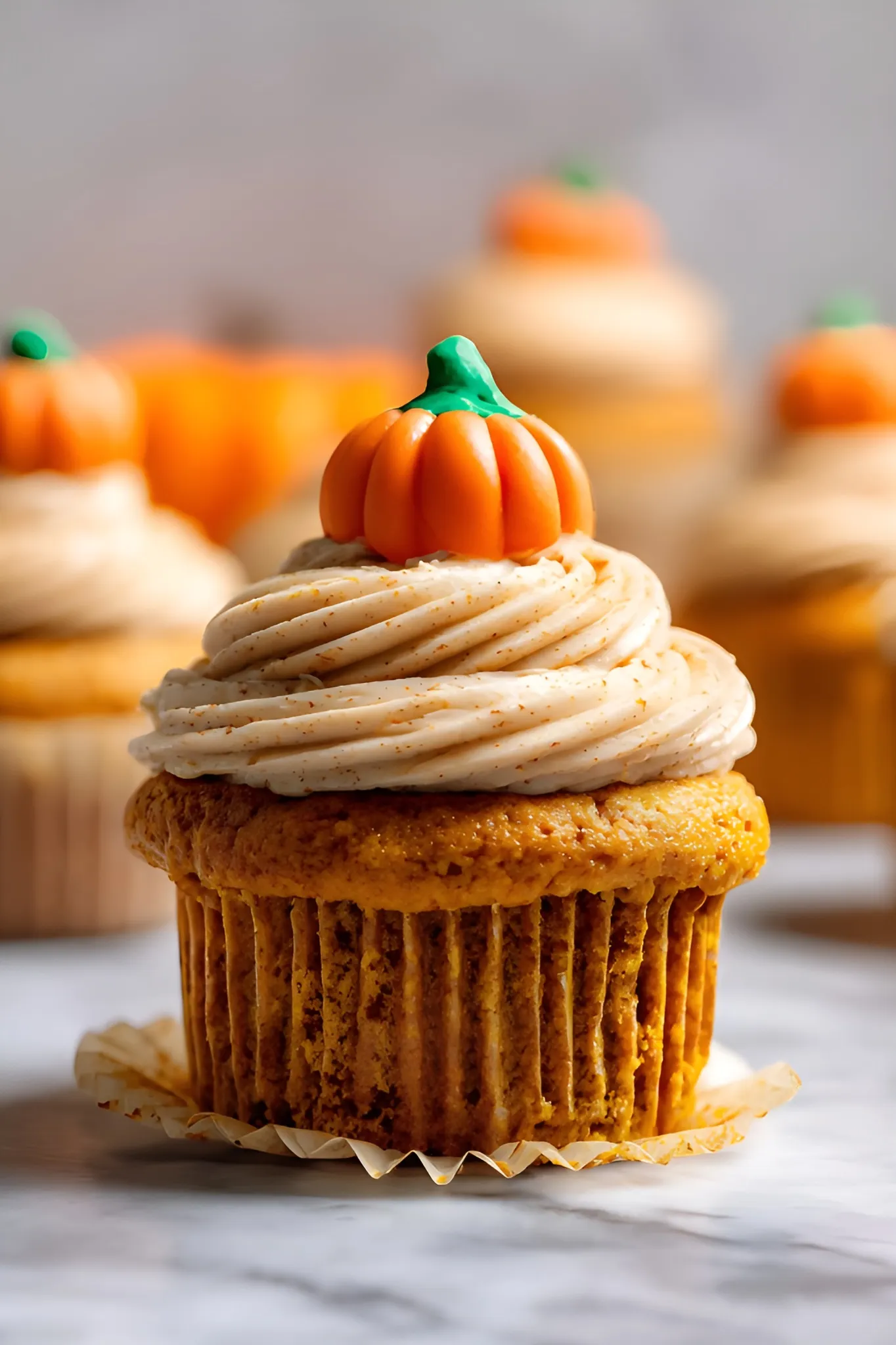 Single pumpkin cupcake with swirled frosting and candy pumpkin topper