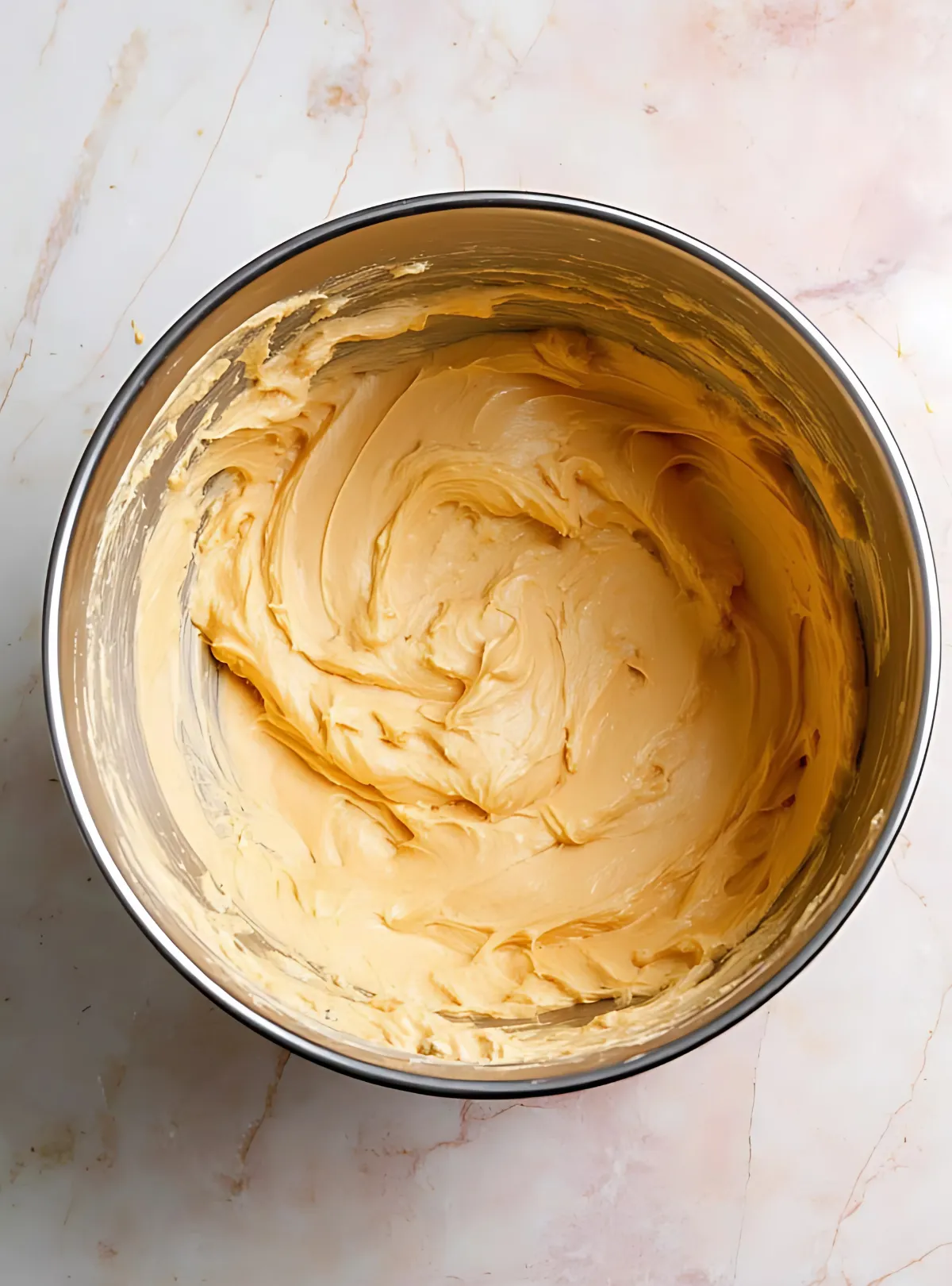 Smooth beige buttercream frosting in mixing bowl