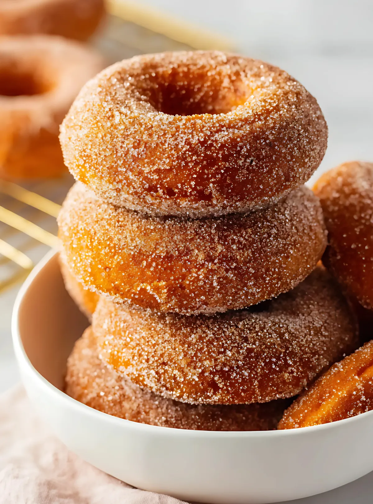 Stack of cinnamon sugar donuts in white bowl
